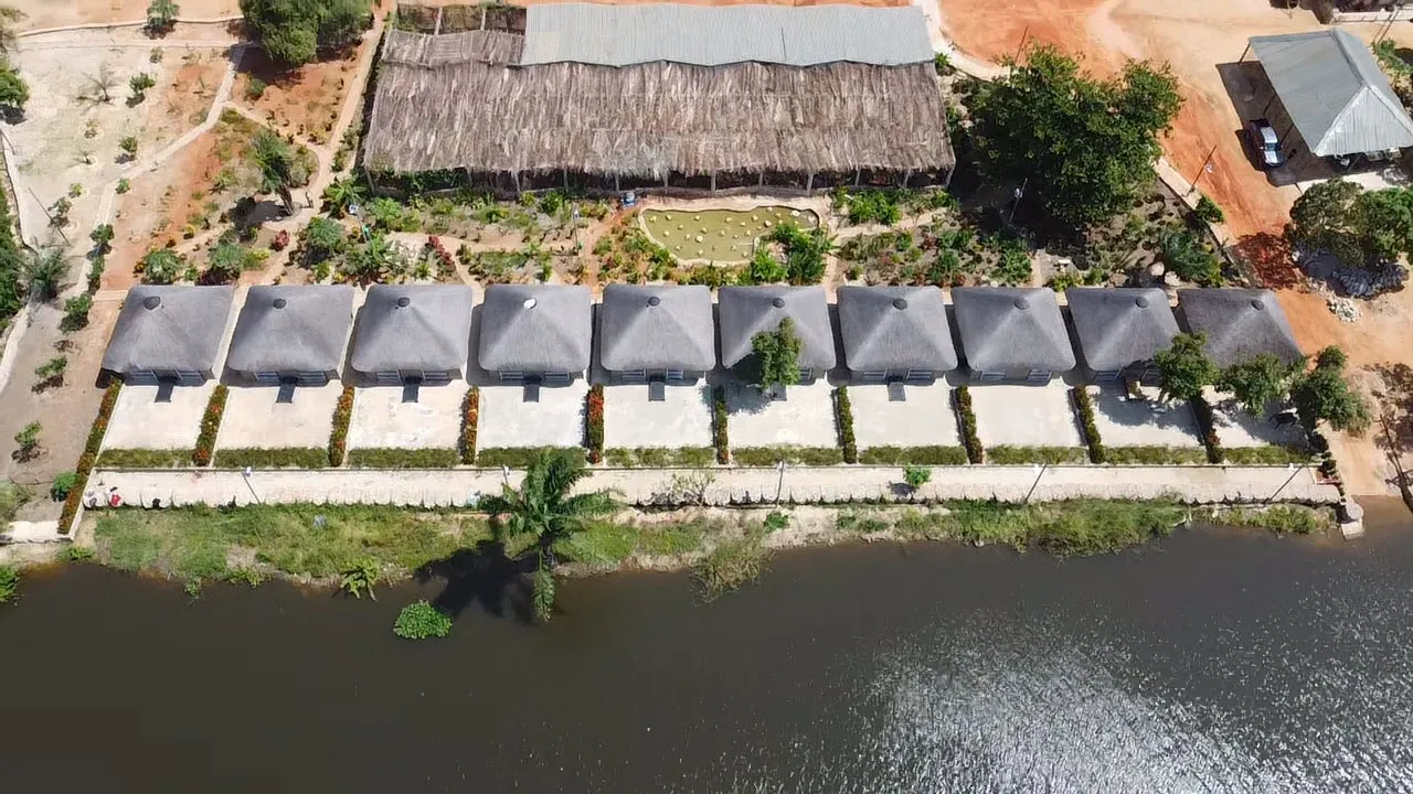Top-down aerial view of the resort's chalet rooftops and dining pavilion by the riverbank