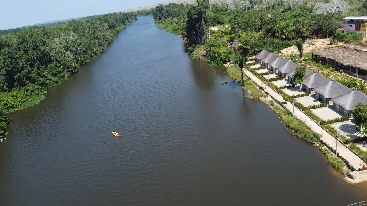 Aerial view of a kayaker on the Kwanza River near the resort's thatched chalets