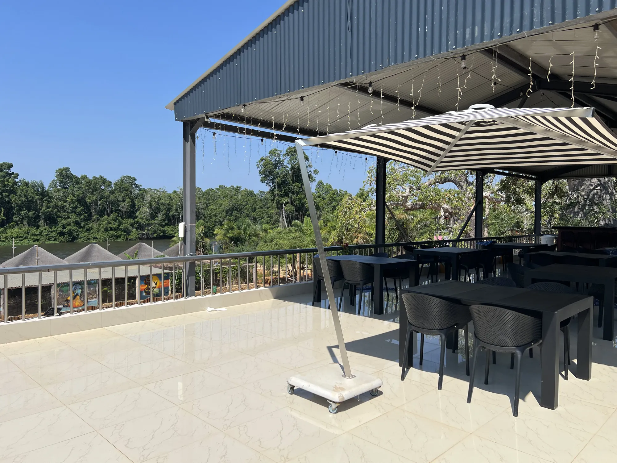 River-view dining terrace with string lights at dusk